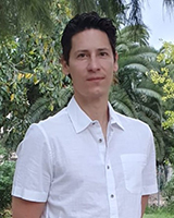 Editor, Sergio Baselga, hispanic man with dark hair, white shirt and foliage in the background